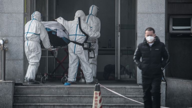 Medical staff carry a patient with the new coronavirus into Wuhan&#39;s Jinyintan hospital 
