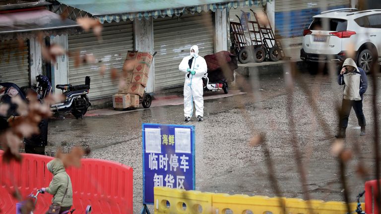 A worker in a protective suit stands outside the closed Wuhan seafood market