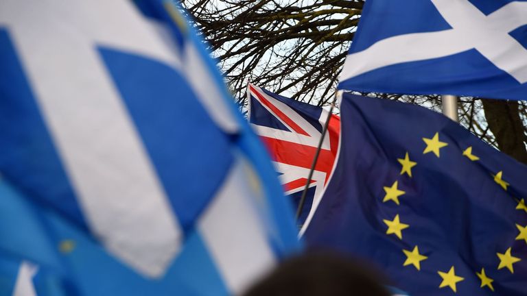 Pro-Union activists wave a Union flag (C) as Scottish Saltire and EU flags fly during an anti-Conservative government, pro-Scottish independence, and anti-Brexit demonstration outside Holyrood, the seat of the Scottish Parliament in Edinburgh on February 1, 2020. - Britain began its post-Brexit uncertain future outside the European Union on Saturday after the country greeted the historic end to almost half a century of EU membership with a mixture of joy and sadness. There were celebrations and tears on Friday as the EU's often reluctant member became the first to leave an organisation set up to forge unity among nations after the horrors of World War II. (Photo by ANDY BUCHANAN / AFP) (Photo by ANDY BUCHANAN/AFP via Getty Images)