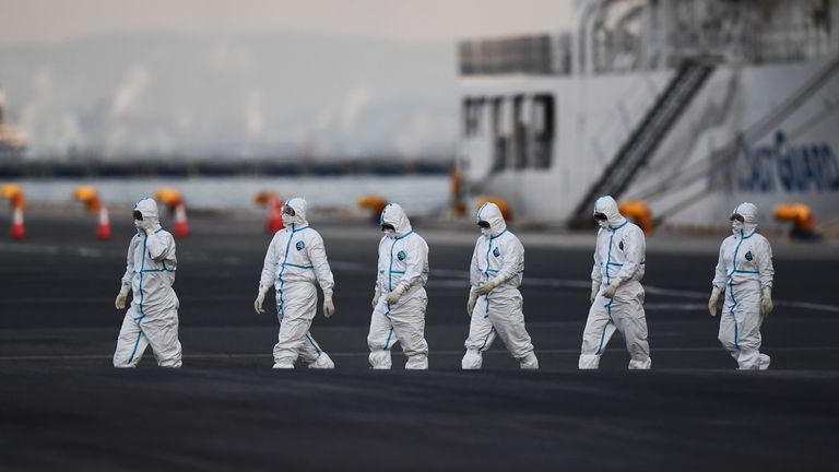 TOPSHOT - People wearing protective suits walk from the Diamond Princess cruise ship, with around 3,600 people quarantined onboard due to fears of the new coronavirus, at the Daikoku Pier Cruise Terminal in Yokohama port on February 10, 2020. - Around 60 more people on board the quarantined Diamond Princess cruise ship moored off Japan have been diagnosed with novel coronavirus, the country's national broadcaster said on February 10, raising the number of infected passengers and crew to around 130. (Photo by CHARLY TRIBALLEAU / AFP) (Photo by CHARLY TRIBALLEAU/AFP via Getty Images)