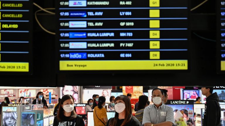 Passengers with protective masks look at a flights information board at Suvarnabhumi airport in Bangkok, on February 24, 2020. - The novel coronavirus has spread to more than 25 countries since it emerged in December and is causing mounting alarm due to new outbreaks in Europe, the Middle East and Asia. (Photo by Hector RETAMAL / AFP) (Photo by HECTOR RETAMAL/AFP via Getty Images)