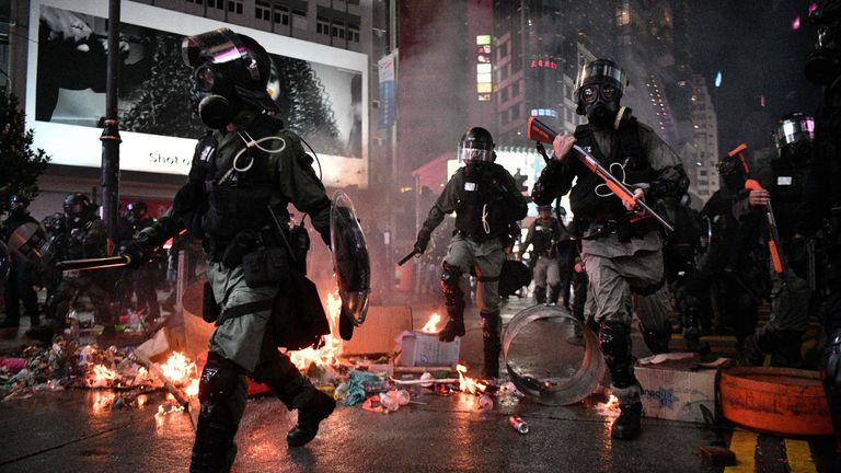 TOPSHOT - Police run past debris set alight by protesters in the Causeway Bay area of Hong Kong on August 31, 2019, as people demonstrate, defying a ban on rallying -- and mounting threats from China -- to take to the streets for a 13th straight weekend. (Photo by Anthony WALLACE / AFP)        (Photo credit should read ANTHONY WALLACE/AFP via Getty Images)