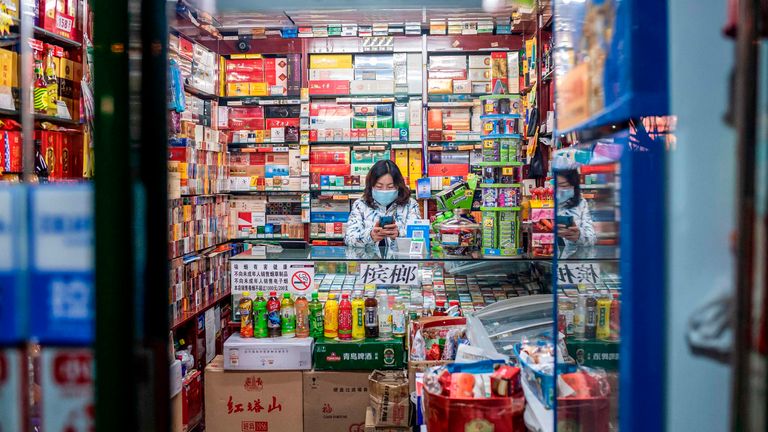 A woman waits for customers in a shop in Beijing