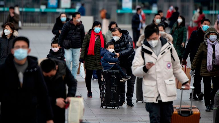 Mask-wearing passengers are seen leaving Beijing railway station 