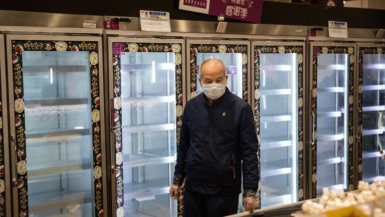 A man stands in front of empty supermarket shelves in Wuhan, the epicentre of the outbreak