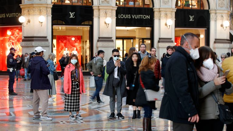 Tourists wearing sanitary masks walk in downtown Milan, Italy