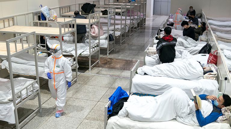 Medical workers in protective suits attend to patients at the Wuhan International Conference and Exhibition Centre, which has been converted into a makeshift hospital