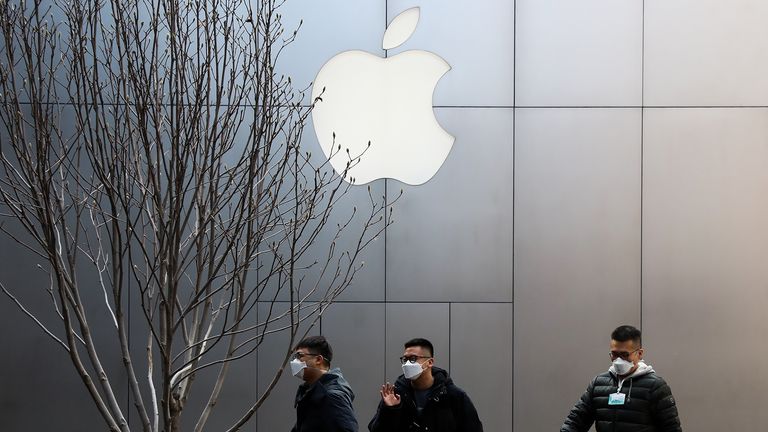 People wearing face masks walk past an Apple store in Beijing on February 17, 2020 in Beijing, China