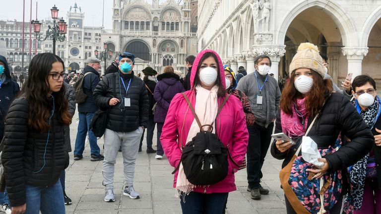 Tourists wear protective masks in Venice after the city&#39;s carnival was cancelled due to COVID-19