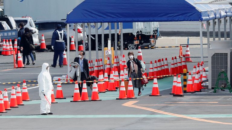A mask-wearing woman is seen back on dry land after the departing the quarantine ship 