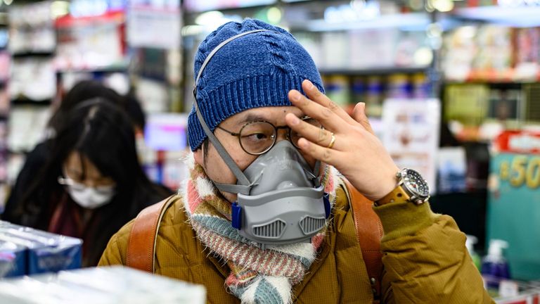 A man is seen with his face covered while buying packets of masks in a Hong Kong pharmacy