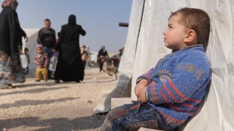 A young child outside a tent in one of the Idlib camps