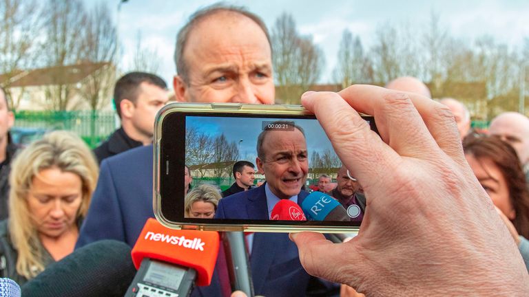Leader of Ireland&#39;s Fianna Fail party, Micheal Martin (C) is filmed as he speaks to members of the media outside the count centre in Cork