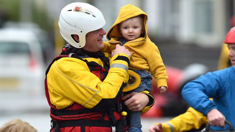 One-year-old Blake is carried by a rescue worker as emergency services continue to take families to safety, after flooding in Nantgarw, Wales, as Storm Dennis hit the UK.