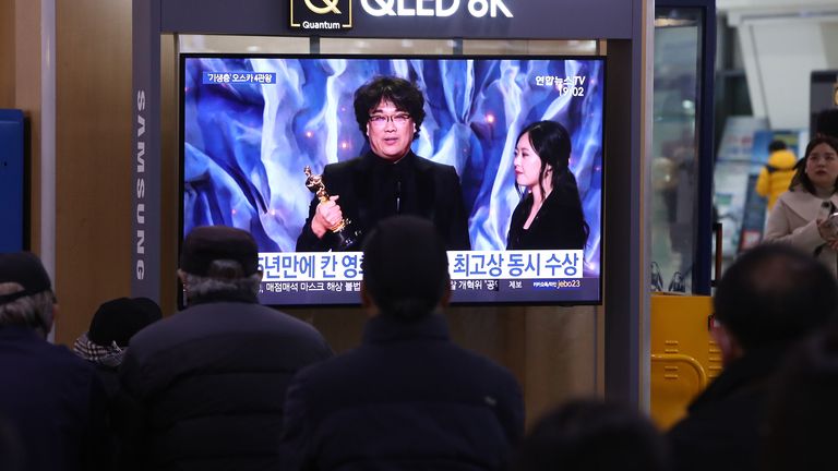 People watch a TV screen showing images of South Korean director Bong Joon Ho at the Seoul Railway Station on February 10, 2020 in Seoul, South Korea. Bong Joon-ho&#39;s "Parasite" has bagged four Oscar titles, becoming the first non-English language film to win best picture