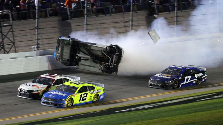 DAYTONA BEACH, FLORIDA - FEBRUARY 17: Denny Hamlin, driver of the #11 FedEx Express Toyota, wins over Ryan Blaney, driver of the #12 Menards/Peak Ford, as Ryan Newman, driver of the #6 Koch Industries Ford, crashes and flips behind them during the NASCAR Cup Series 62nd Annual Daytona 500 at Daytona International Speedway on February 17, 2020 in Daytona Beach, Florida. (Photo by Chris Graythen/Getty Images)