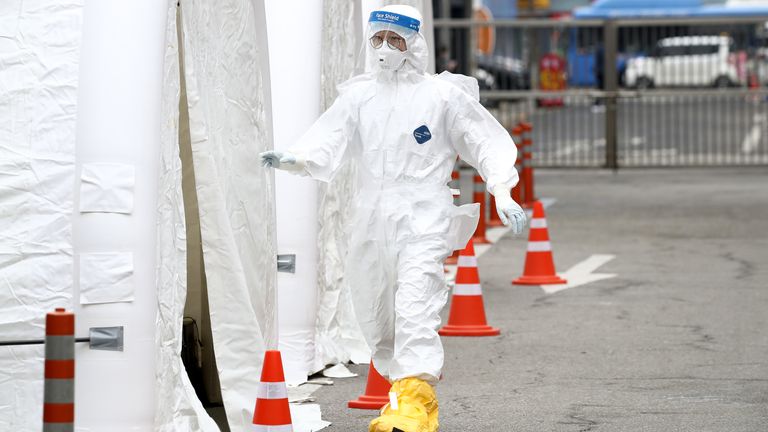 A medic wearing full protective gear walks into a preliminary testing facility in Seoul, South Korea