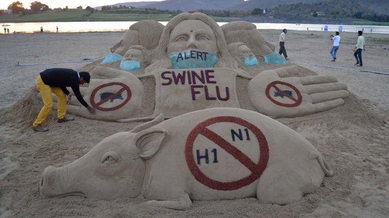 Indian sand artist Sudarsan Pattnaik finishes a sculpture promoting swine flu awareness