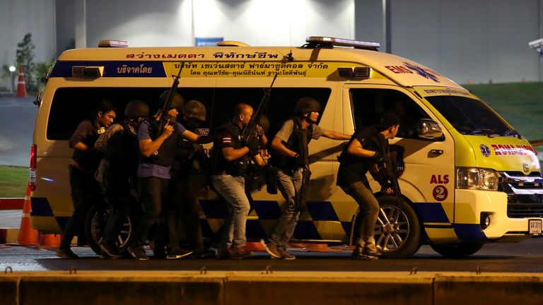 Thail security forces take cover behind an ambulance as they hunt the suspect