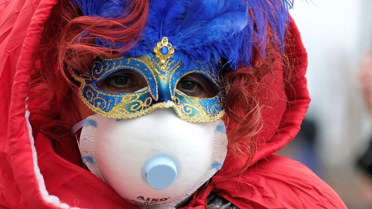 Masked carnival reveller wears protective face mask at Venice Carnival, which the last two days of, as well as Sunday night&#39;s festivities, have been cancelled because of an outbreak of coronavirus, in Venice, Italy February 23, 2020