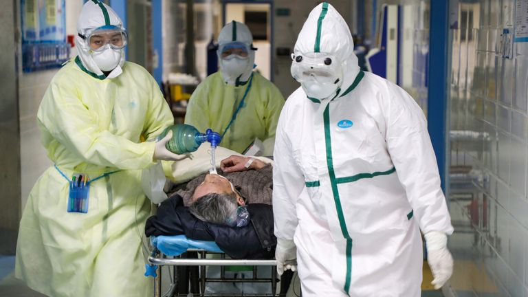 Medical workers in protective suits move a patient in a hospital in Wuhan