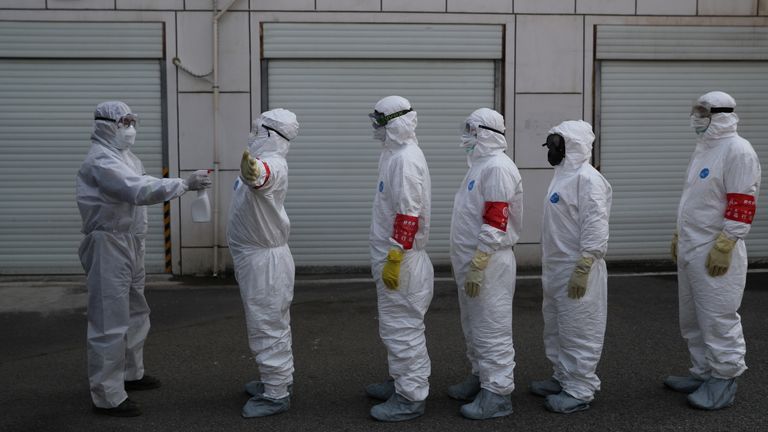Volunteers in protective suits are disinfected in Wuhan