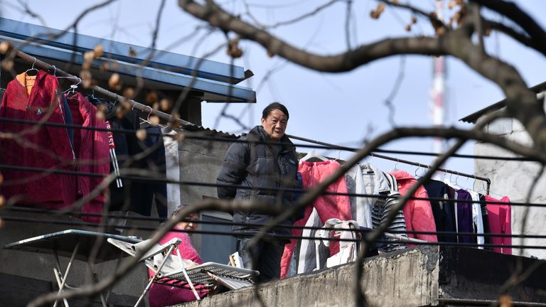 A man stands next to laundry on a balcony at a residential compound in Wuhan, the epicentre of the novel coronavirus disease (COVID-19) outbreak, Hubei province, China, March 10, 2020. REUTERS     SEARCH "WUHAN HOMES" FOR THIS STORY. SEARCH "WIDER IMAGE" FOR ALL STORIES.  CHINA OUT.