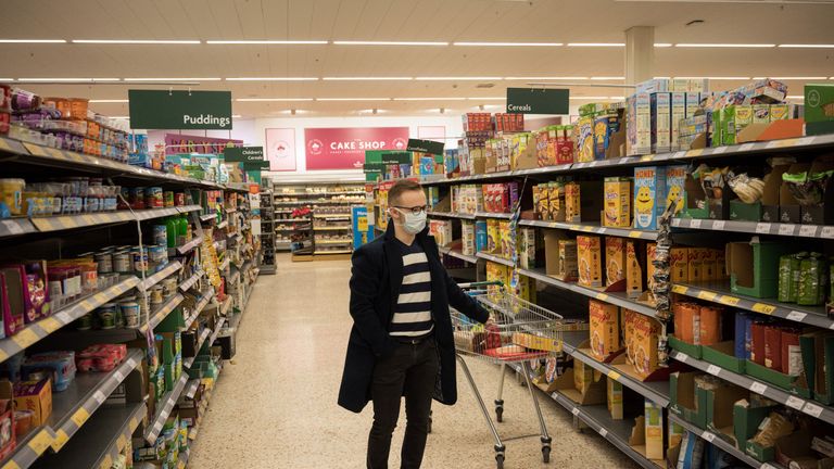 A man wearing a mask as a precaution against covid-19, stands with a shopping trolleys inside a Morrisons supermarket in the centre of York, northern England, on March 19, 2020. - Britain's supermarkets on Wednesday stepped up efforts to safeguard supplies, especially for vulnerable and elderly customers, as the sector battles stockpiling caused by coronavirus panic. (Photo by OLI SCARFF / AFP) (Photo by OLI SCARFF/AFP via Getty Images)