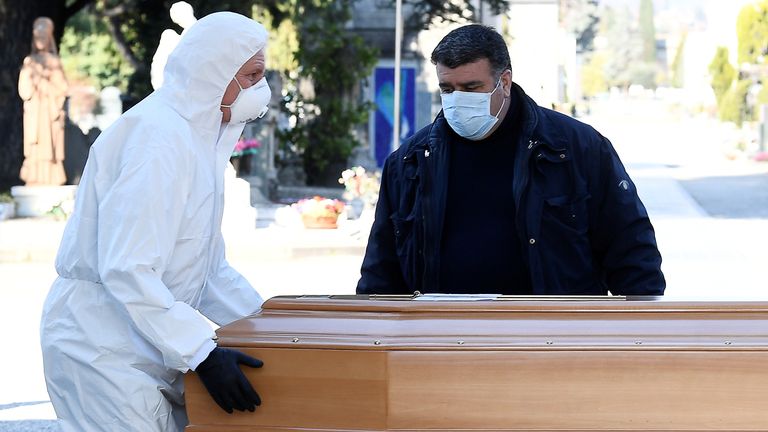 Workers transport a coffin into a cemetery