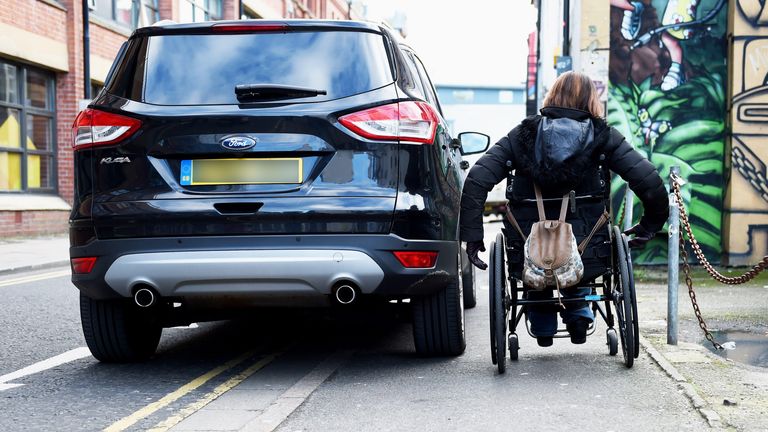 HR55PP Wheelchair user struggles to pass by badly parked car on pavement and double yellow lines in Brighton UK