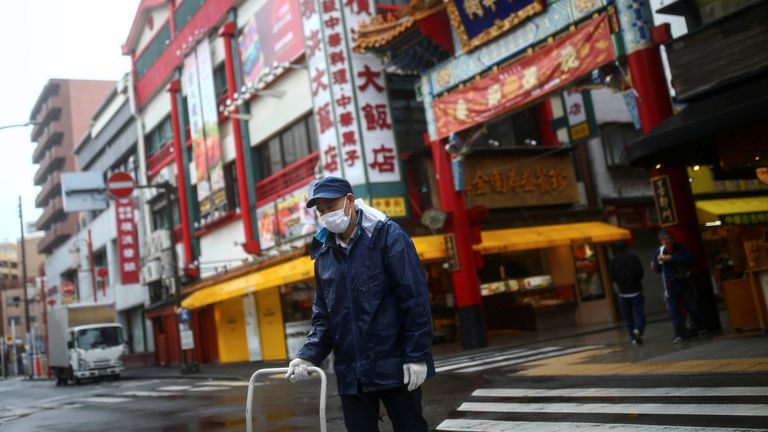 A worker, wearing protective face mask following an outbreak of the coronavirus disease (COVID-19), is pictured on an almost empty street in Yokohama?s Chinatown, south of Tokyo, Japan March 10, 2020. REUTERS/Edgard Garrido