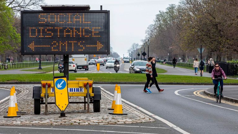 A sign notifies passers by of the 2 meter social distancing measures in place, as people exercise in Phoenix Park in Dublin, on March 25, 2020, after Ireland introduced measures to help slow the spread of the novel coronavirus