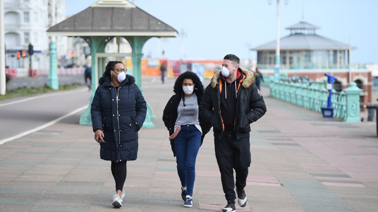 People stroll across Brighton seafront during the coronavirus outbreak