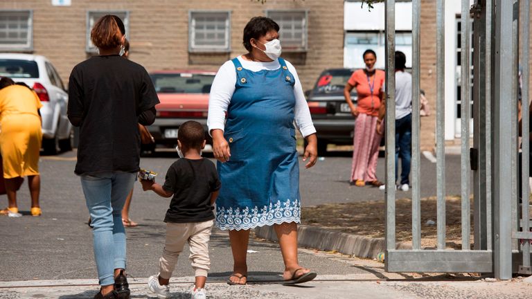 A woman wearing a protective face mask walks out walk out of the Belhar Clinic in Belhar, near Cape Town