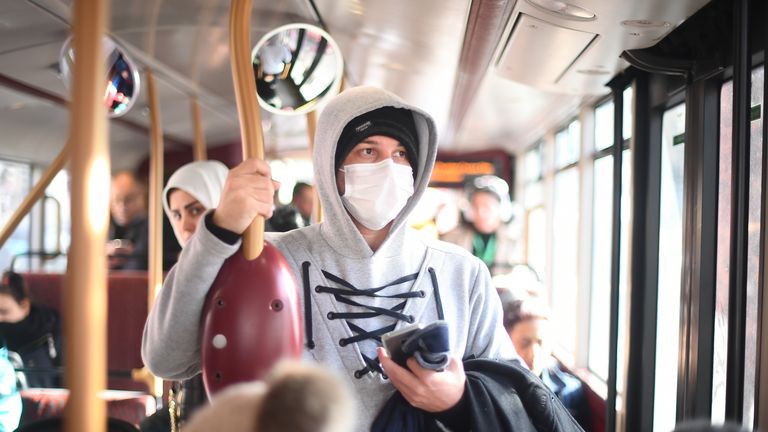 A mask-wearing passenger is seen on a bus as coronavirus cases continue to rise