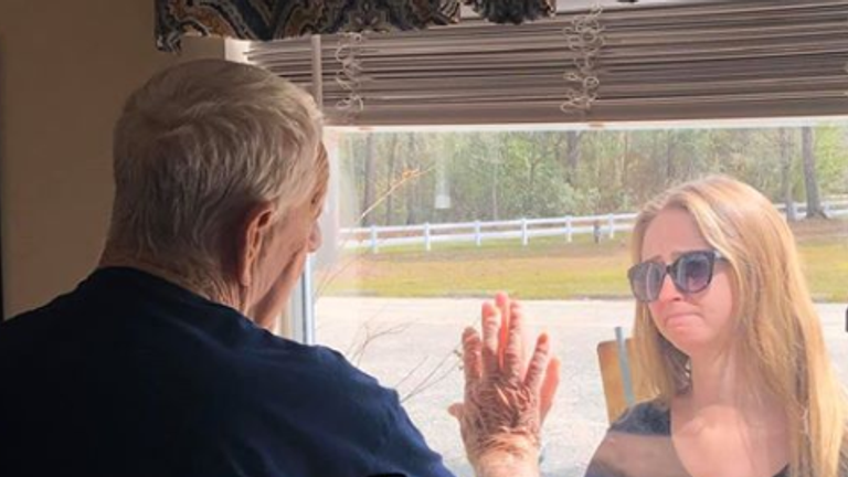 The pair touched hands either side of the window. Pic: Premier Living and Rehab Center 
