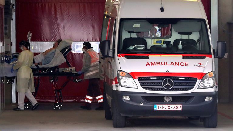 Medics wearing protective masks transport a patient on a stretcher at a hospital in Aalst, Belgium