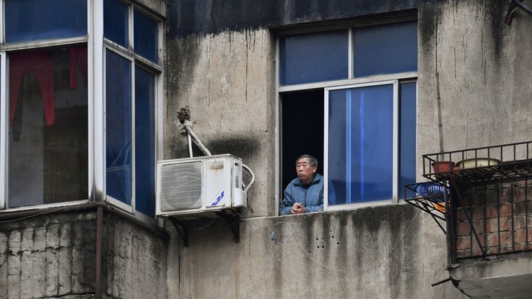 A man looks out of the window at a residential compound in Wuhan