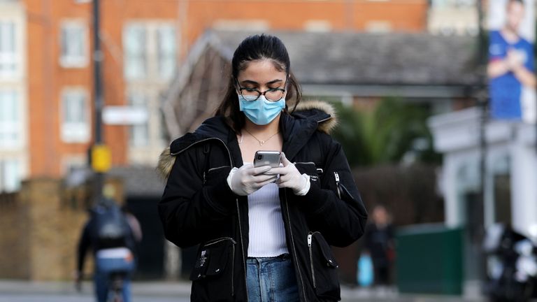 A woman wearing a protective mask walks near Stamford Bridge football stadium in London on March 13, 2020. - The English Premier League suspended all fixtures until April 4 on Friday after Arsenal manager Mikel Arteta and Chelsea winger Callum Hudson-Odoi tested positive for coronavirus. (Photo by ISABEL INFANTES / AFP) (Photo by ISABEL INFANTES/AFP via Getty Images)
