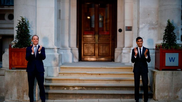 Britain's Foreign Secretary Dominic Raab (L) and Britain's Chancellor of the Exchequer Rishi Sunak (R) take part in a national "clap for carers" to show thanks for the work of Britain's National Health Service (NHS) workers and frontline medical staff around the country as they battle with the novel coronavirus pandemic, on the steps of the Foreign and Commonwealth Office (FCO) in central London on April 16, 2020. - Britain on Thursday extended its lockdown to tackle the coronavirus for "at least the next three weeks", as it remains among the countries worst-hit by the pandemic with hundreds dying daily from the disease. (Photo by Tolga Akmen / POOL / AFP) (Photo by TOLGA AKMEN/POOL/AFP via Getty Images)