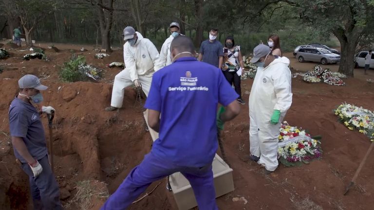 Cemetery workers lower a coffin into a grave