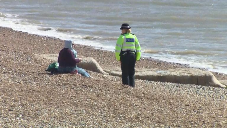 A police officer speaks to a woman sitting on beach at Brighton during lockdown