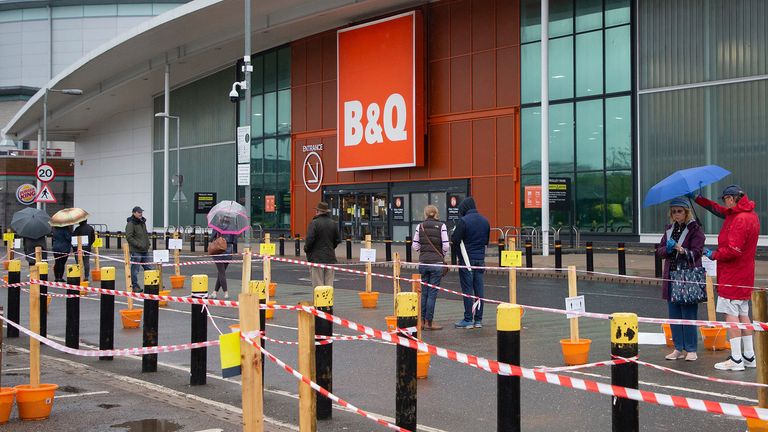 Members of the public shelter under umbrellas as they queue outside a branch of B&Q in Charlton, South London. Pic: George Cracknell Wright/LNP/Shutterstock 