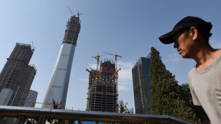 This picture taken on May 25, 2017 shows a man walking past a construction project in Beijing&#39;s central business district, as China Zun (2nd L), the city&#39;s tallest building, is seen in the background
