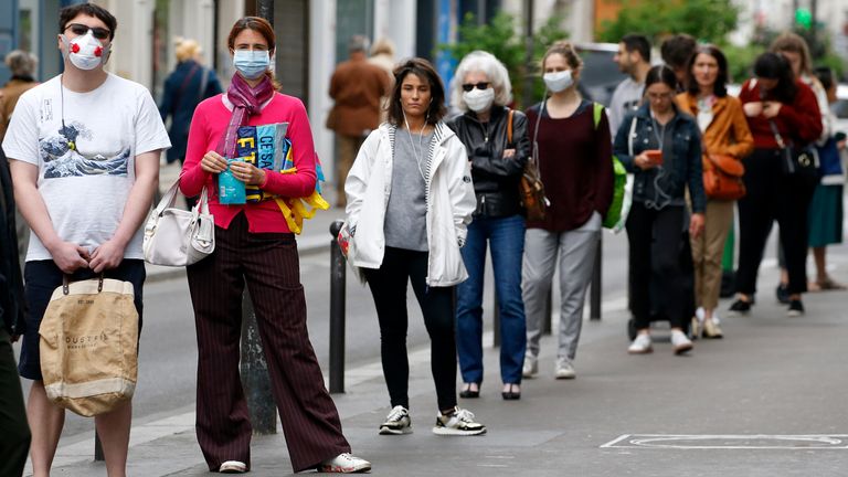 Mask-wearing shoppers queue outside a shop in Paris during lockdown measures 