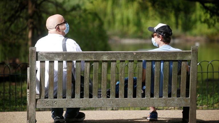 Two people wearing masks in St James&#39;s Park in London