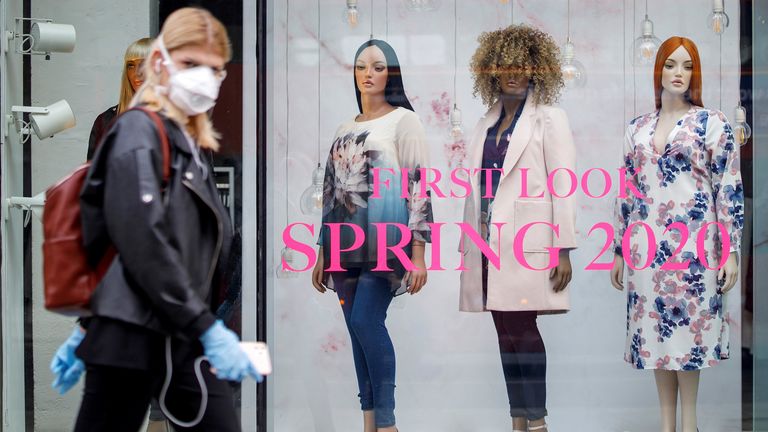 A woman with face covering walks past a store in central London