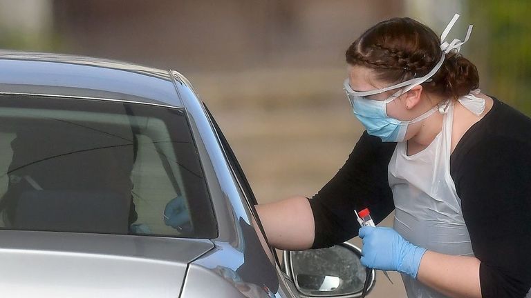 A worker in PPE including gloves, a face mask, eye protection and an apron, swabs an NHS worker at a drive-in facility to set up to test for the novel coronavirus COVID-19, in the car park of Chessington World of Adventures theme park, in Chessington, Greater London on April 2, 2020. - Prime Minister Boris Johnson said Britain would "massively increase testing" amid a growing wave of criticism on Thursday about his government&#39;s failure to provide widespread coronavirus screening. (Photo by Ben S