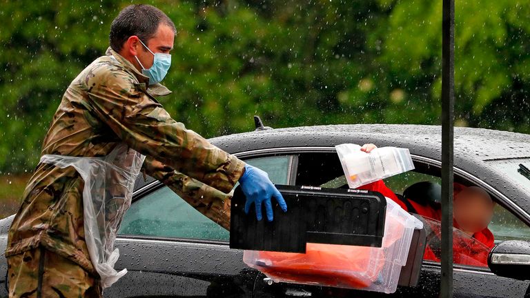 A soldier of the Royal Welsh regiment accepts the test of a key workerat a drive-in testing facility for the novel coronavirus COVID-19 in Salisbury, southwest England on April 30, 2020. - Britain&#39;s death toll from the coronavirus outbreak jumped to 26,097 on Wednesday -- the second-highest in Europe behind Italy and third-highest in the world -- as the government took into account fatalities outside hospital, including care homes, for the first time. (Photo by Adrian DENNIS / AFP) (Photo by ADRIAN DENNIS/AFP via Getty Images)