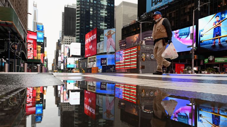 A man crosses the street at a nearly empty Time Square on April 09, 2020 in New York City. 